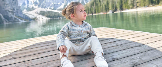 Une petite fille est assise près d'un lac dans les montagnes